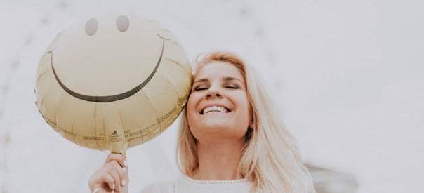 a happy woman holding a balloon with a smiley face